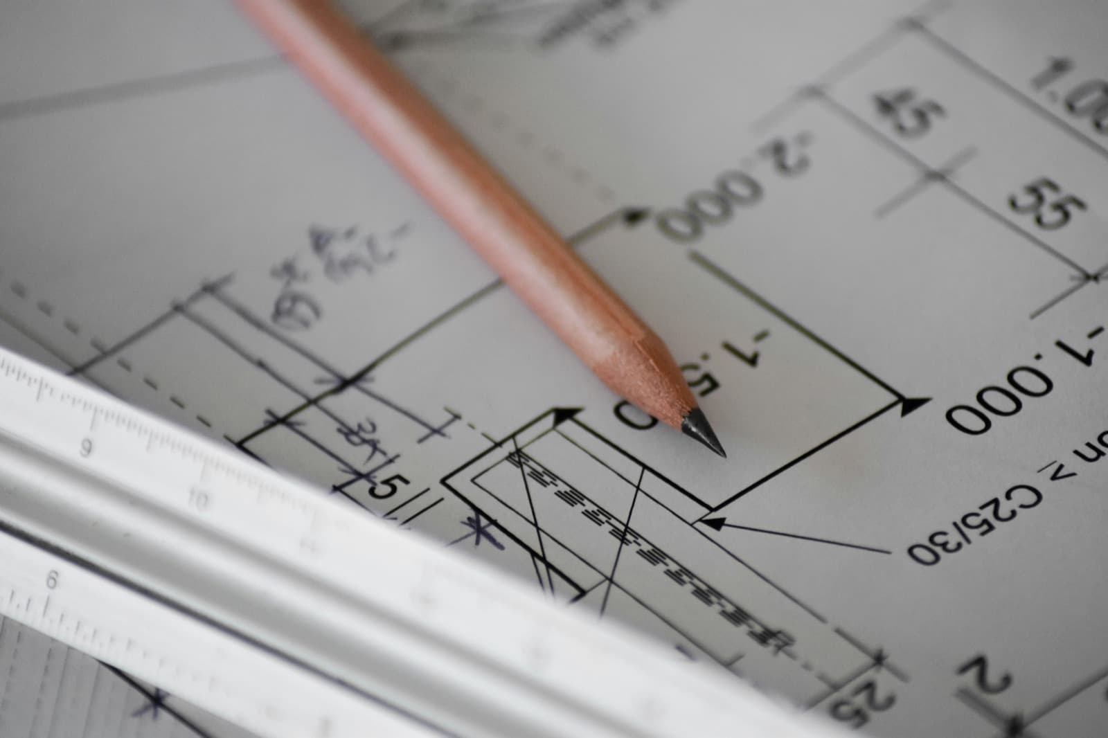 Matita e scalimetro appoggiati su un disegno tecnico con le quote