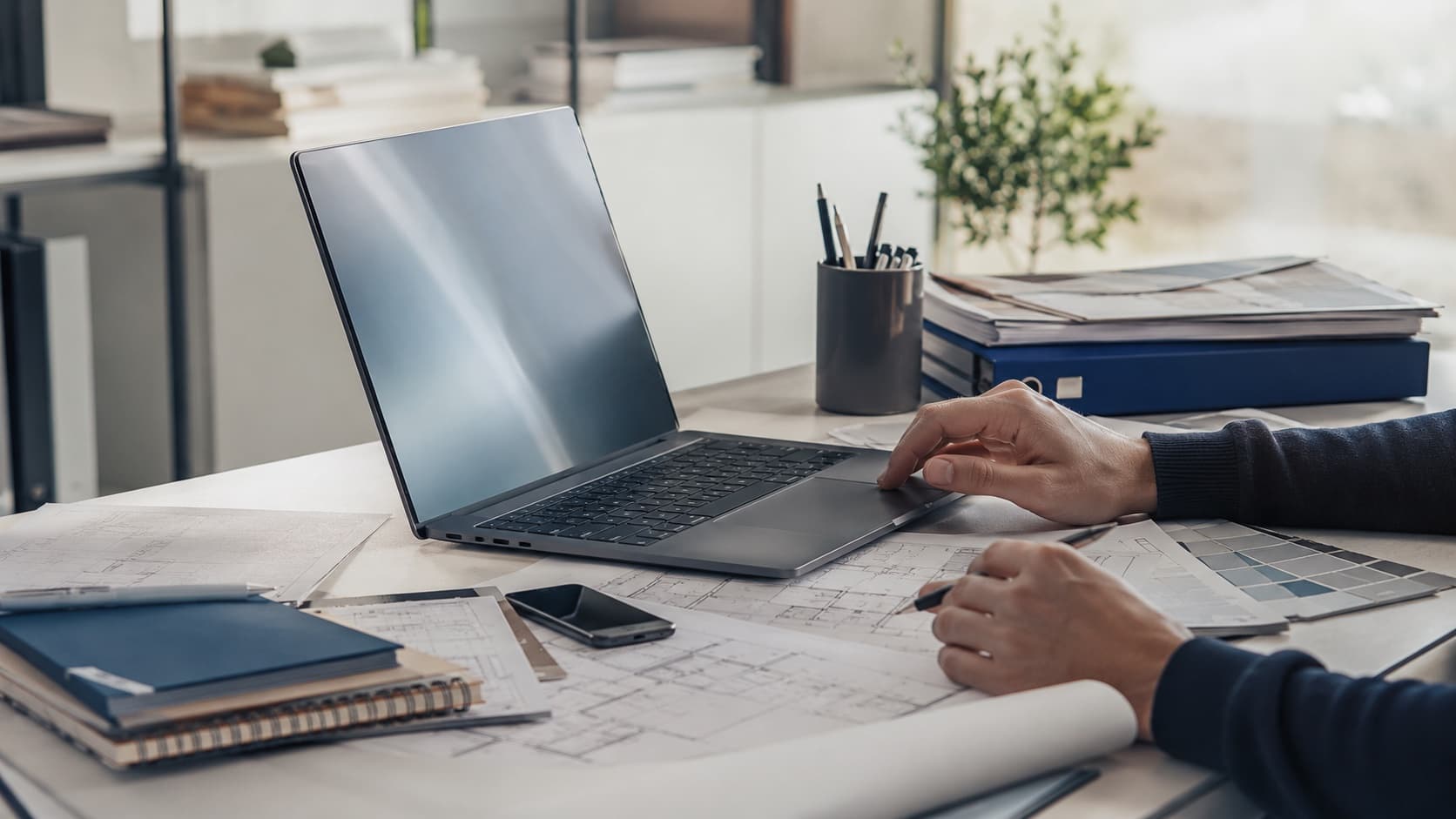 Studio tecnico con laptop, planimetrie, agenda e documenti per organizzare lavori, scadenze e pagamenti